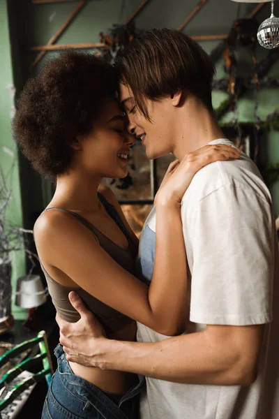 Heureux couple multiethnique debout face à face et embrasser les yeux fermés dans le studio d'art — Photo de stock