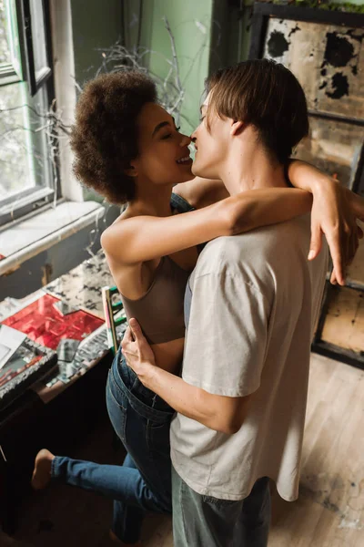 Sexy interracial artists embracing face to face in art workshop — Stock Photo