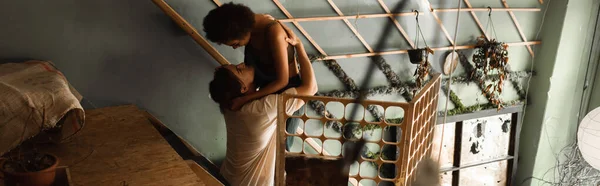 High angle view of young interracial artists embracing near decorative lattice in workshop, banner — Stock Photo
