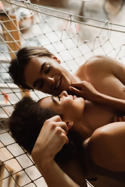 Shirtless man and pretty african american woman smiling at each other in hammock — Stock Photo