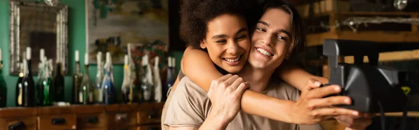 Eccitata donna afroamericana che si fa selfie con ragazzo sorridente sulla fotocamera vintage in officina, banner — Foto stock