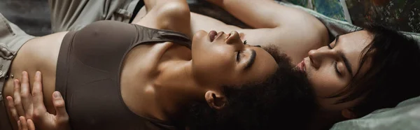 Vue du dessus du jeune artiste torse nu embrassant séduisante petite amie afro-américaine dans l'atelier, bannière — Photo de stock