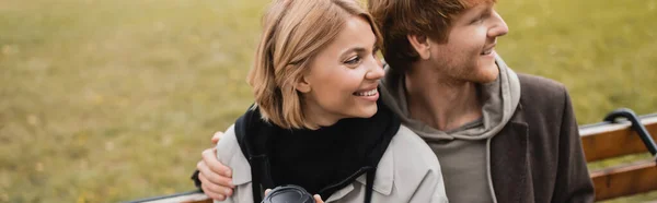 Щасливий молодий чоловік обіймає блондинку в автентичному пальто, банер — стокове фото