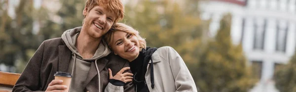 Glückliche junge Frau umarmt Freund mit Pappbecher mit Coffee to go im Park, Banner — Stockfoto