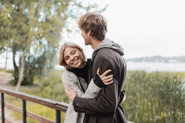 Donna bionda che sorride e abbraccia l'uomo rossa durante la data sul ponte — Foto stock