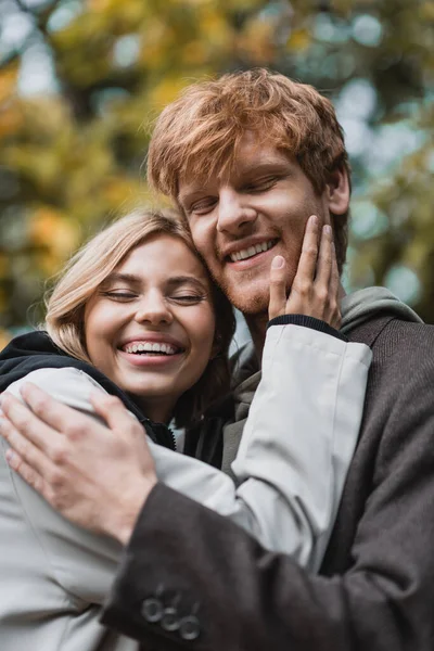 Freudiges junges Paar mit geschlossenen Augen, die sich beim Date umarmen — Stockfoto