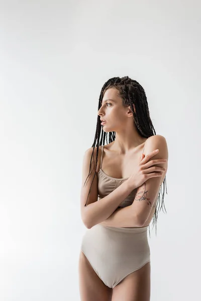 Side view of tattooed woman in underwear looking away isolated on grey — Stock Photo