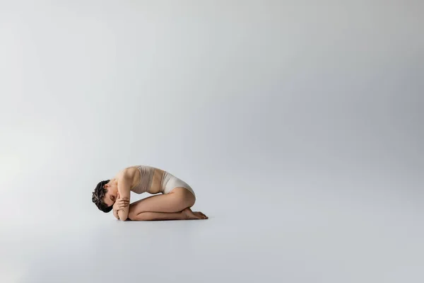 Young woman in beige underwear posing on grey background — Stock Photo