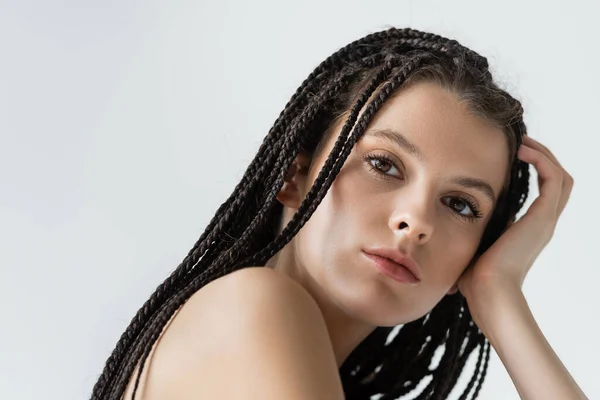 Retrato de mujer joven con trenzas mirando a la cámara aislada en gris - foto de stock