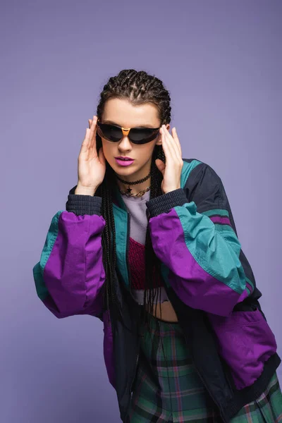 Modèle élégant en lunettes de soleil et veste de sport rétro isolé sur violet — Photo de stock