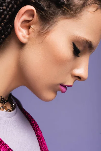 Side view of woman with makeup and necklaces isolated on purple — Stock Photo