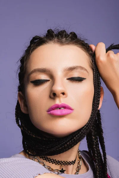 Retrato de mulher com maquiagem e tranças posando com olhos fechados isolados em roxo — Fotografia de Stock