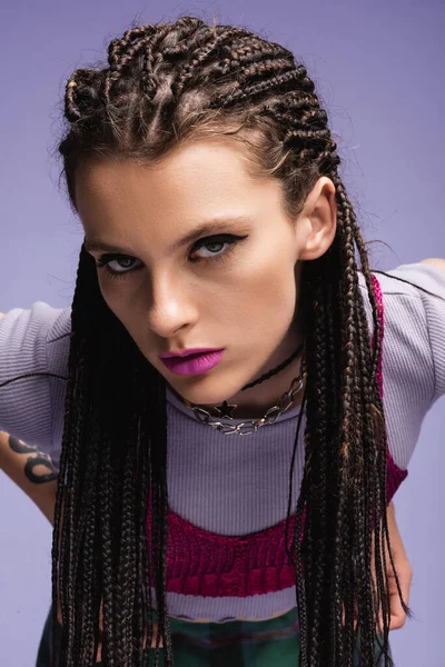 Retrato de mulher na moda com dreadlocks e maquiagem olhando para a câmera isolada em roxo — Fotografia de Stock