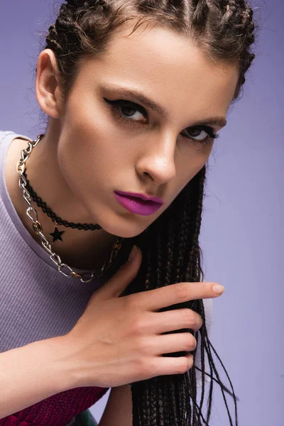 Retrato de mulher elegante em colares e maquiagem olhando para a câmera isolada em roxo — Fotografia de Stock