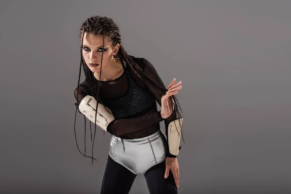 Mulher futurista com dreadlocks posando em macacão apertado e shorts de prata isolado em cinza — Fotografia de Stock