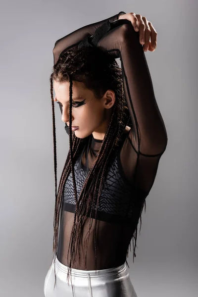 Futuristic style woman with dreadlocks posing with hands above head isolated on grey — Stock Photo