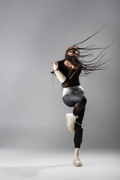 Longitud completa de la mujer con rastas posando en traje futurista sobre fondo gris - foto de stock