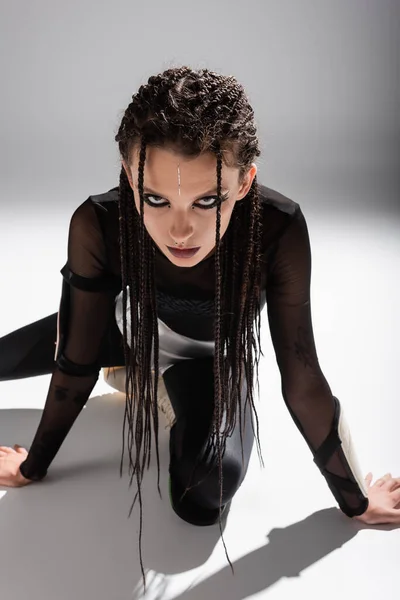 Futuristic style woman with dreadlocks posing in black tight jumpsuit on grey background — Stock Photo