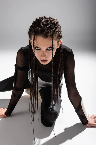 Mulher estilo futurista com dreadlocks posando em macacão apertado preto no fundo cinza — Fotografia de Stock