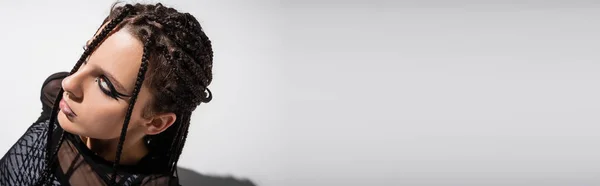 Vista de ángulo alto de la mujer joven con rastas y maquillaje futurista aislado en gris, bandera - foto de stock