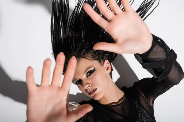 Vista dall'alto della donna con le mani tese e dreadlocks sdraiato su sfondo bianco con ombra — Foto stock