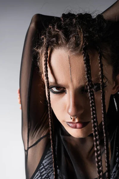 Portrait of brunette woman with braided dreadlocks and makeup looking at camera isolated on grey — Stock Photo