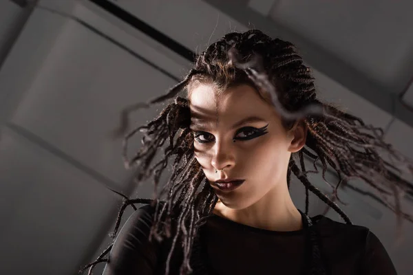 Porträt einer jungen Frau mit Dreadlocks und ausdrucksstarkem Make-up auf grauem Hintergrund — Stockfoto