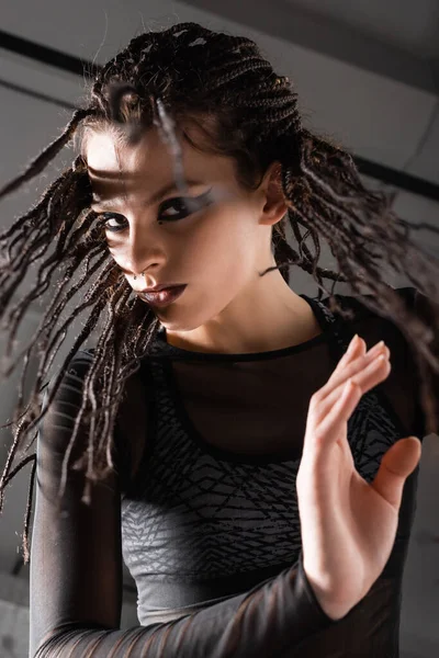Low angle view of woman with braids posing in black clothes on grey background — Stock Photo