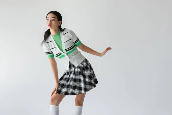 Young asian woman in plaid skirt posing isolated on grey — Stock Photo