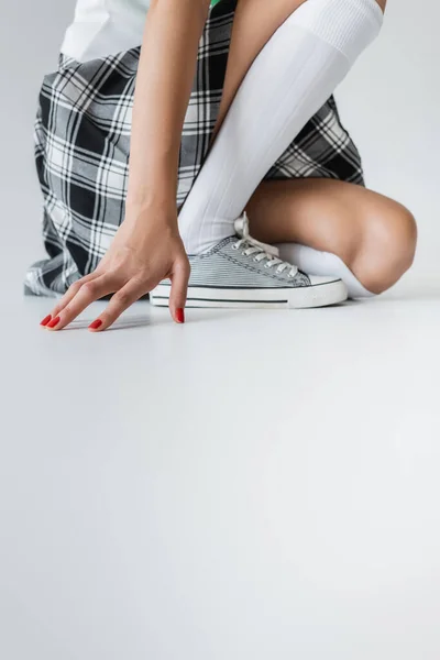Vista ritagliata della donna in gonna a quadri e calzini al ginocchio su sfondo grigio — Foto stock