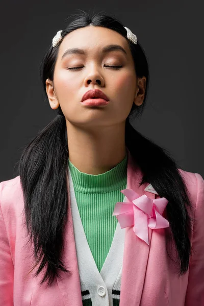 Portrait of stylish asian model in jacket closing eyes isolated on grey — Stock Photo