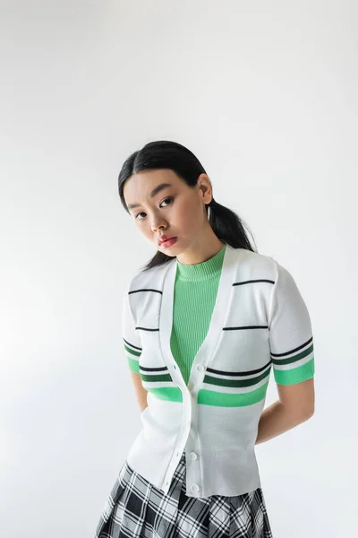 Portrait of young asian woman in cropped cardigan looking at camera isolated on grey — Stock Photo