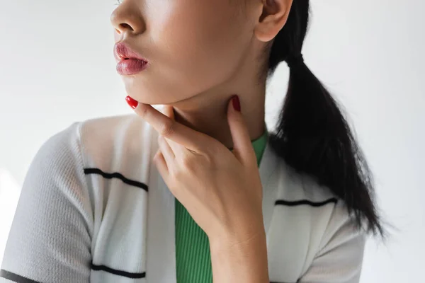 Cropped view of young woman with red manicure touching chin isolated on grey — Stock Photo