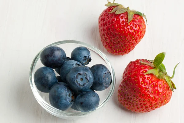 Blueberries and tow strawberries — Stock Photo, Image