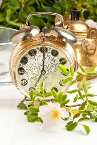 Old alarm-clock and teapot with flowers — Stock Photo, Image