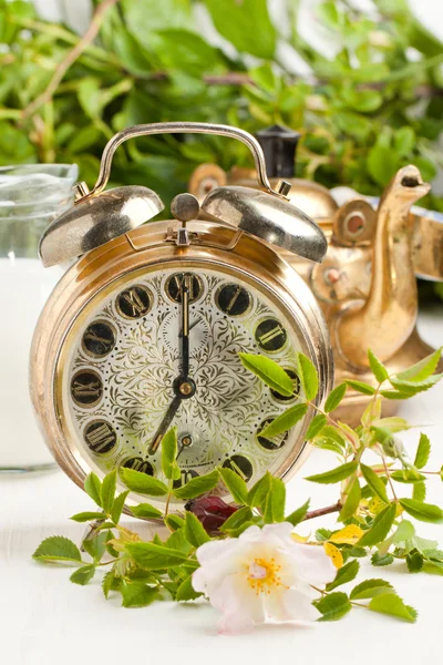 Old alarm-clock and teapot with flowers — Stock Photo, Image