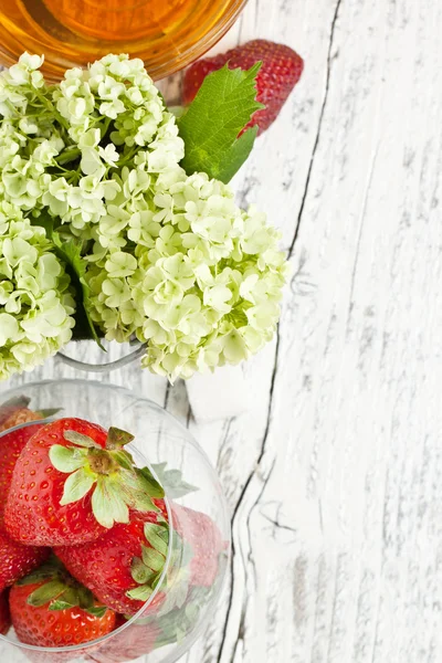 Flores y fresas sobre madera blanca — Foto de Stock