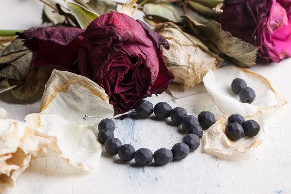 Black beads with dry roses — Stock Photo, Image