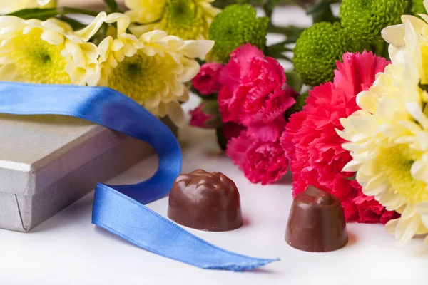 Caramelle al cioccolato e fiori sopra bianco — Foto Stock