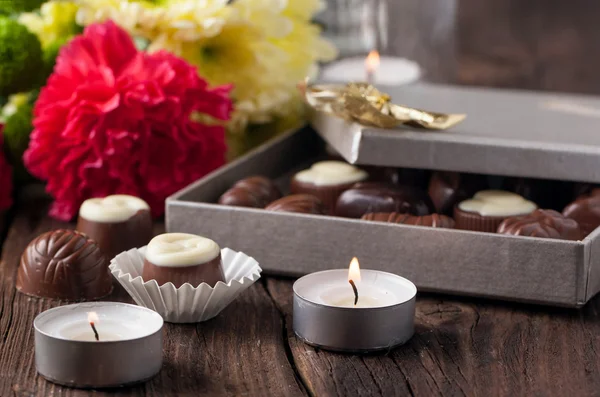 Chocolate candy, candles and flowers — Stock Photo, Image