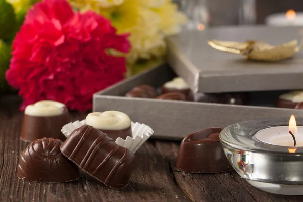 Chocolate candy and flowers — Stock Photo, Image