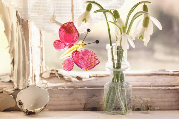 Iterior window with glass butterfly and snowdrops — Stock Photo, Image