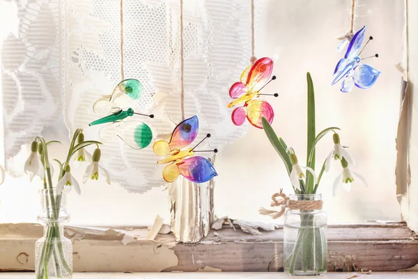 Iterior window with glass butterflies and snowdrops — Stock Photo, Image