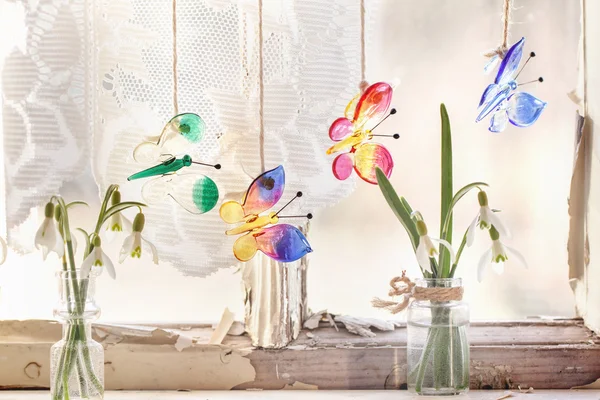 Внешнее окно со стеклянными бабочками и подснежниками — стоковое фото