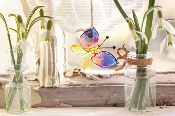 Iterior window with glass butterfly and snowdrops — Stock Photo, Image