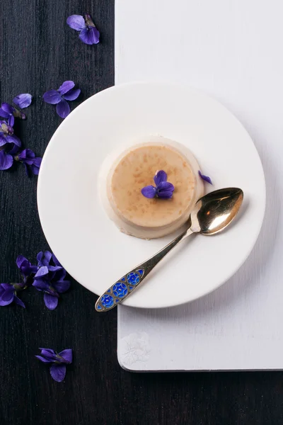 Caramel pannacotta with violet flowers