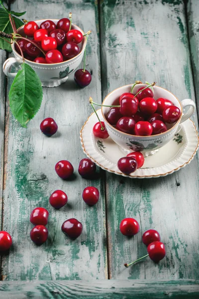 Свежие вишни в стакане старинного чая — стоковое фото