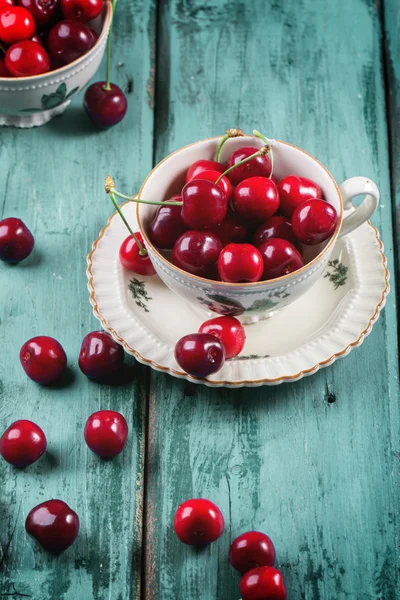 Fresh cherries in vintage tea cup — Stock Photo, Image