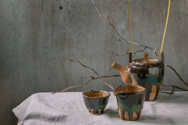 El yapımı seramik çaydanlık. Keten masa örtüsünün üzerinde duran çay seremonisi için bir fincan sıcak yeşil çay..