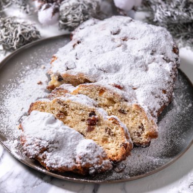 Geleneksel ev yapımı Alman Noel pastası pişirme tabağında gümüş xmas süslemeleriyle beyaz mermer arka planda. Kare resim